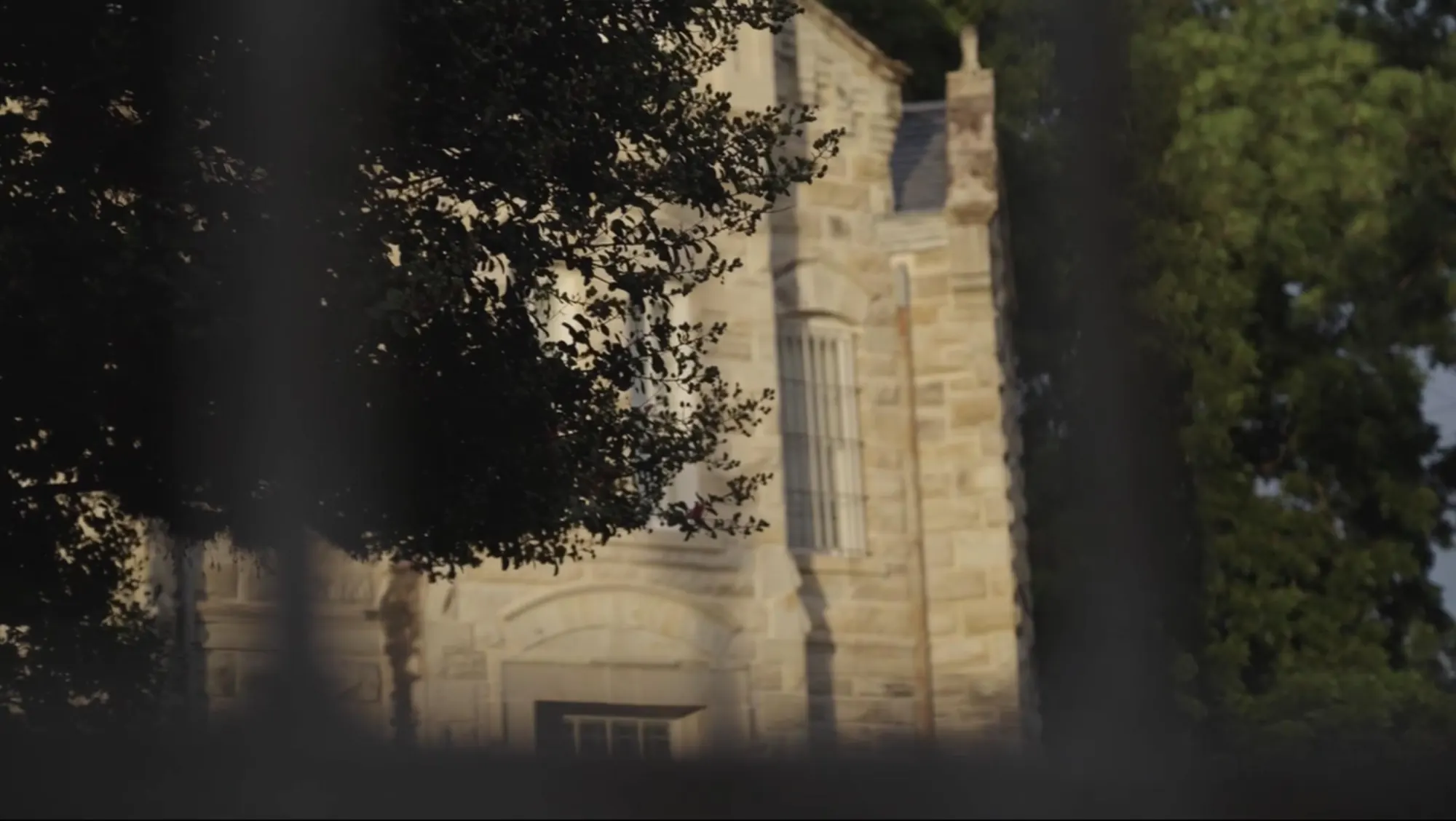 Stone jailhouse framed by live oaks at golden hour